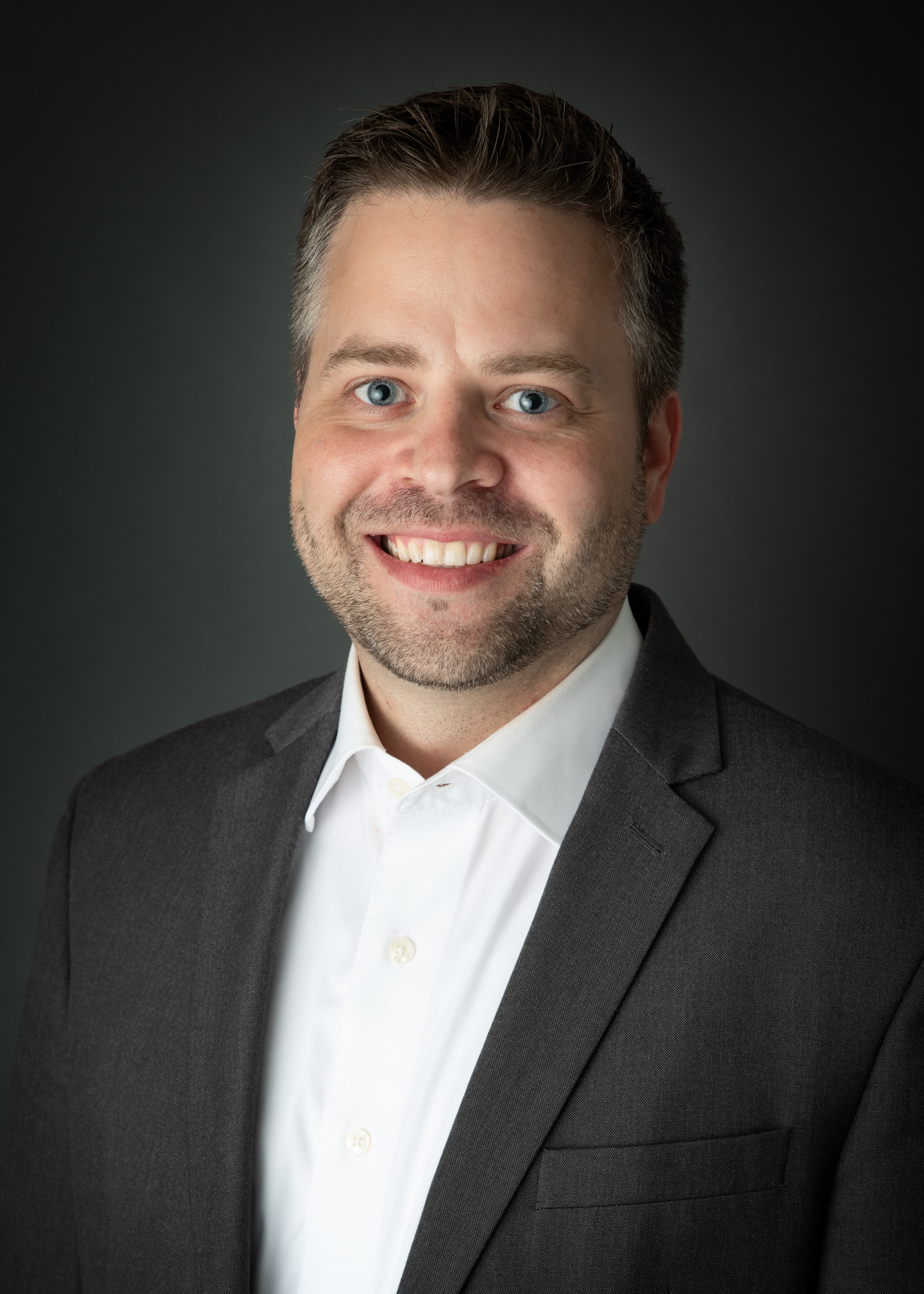 a man in a suit smiling for the camera